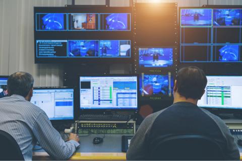 Photo of news broadcast editorial production team viewing monitors and planning stories